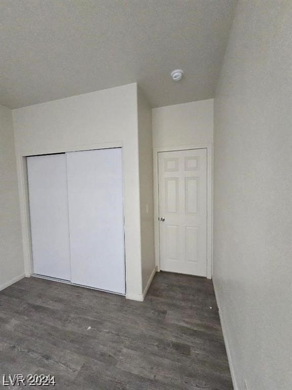 unfurnished bedroom featuring wood finished floors, a closet, and baseboards