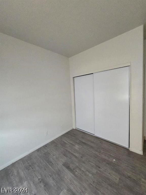 unfurnished bedroom with wood finished floors, baseboards, a closet, and a textured ceiling