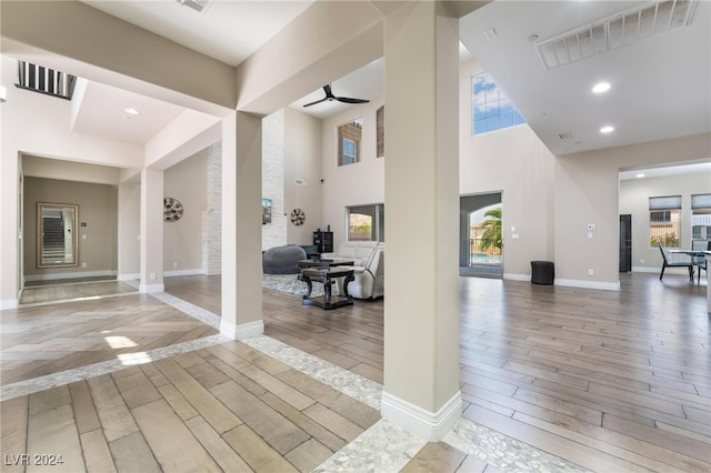 corridor featuring light hardwood / wood-style floors and a towering ceiling