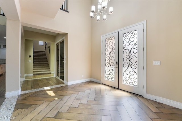 foyer entrance featuring french doors, an inviting chandelier, and light parquet flooring