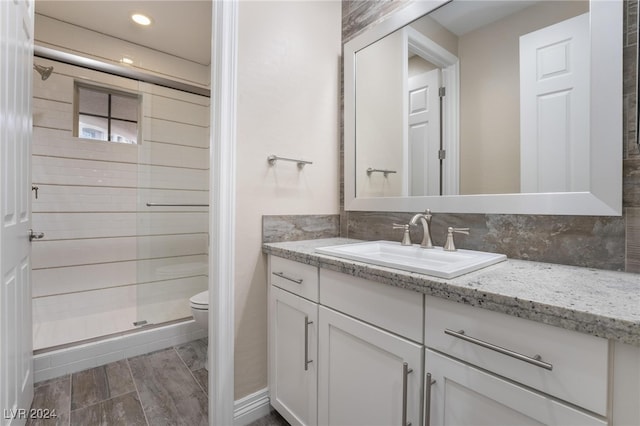 bathroom with wood-type flooring, vanity, toilet, and a shower with door