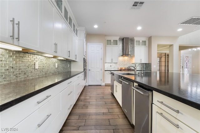 kitchen featuring wall chimney exhaust hood, white cabinetry, appliances with stainless steel finishes, dark hardwood / wood-style floors, and decorative backsplash