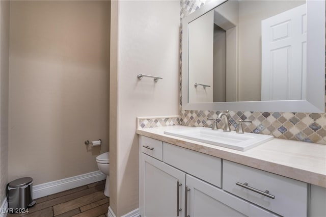 bathroom featuring decorative backsplash, wood-type flooring, vanity, and toilet