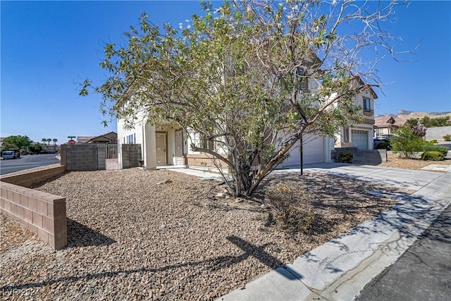 obstructed view of property with a garage, concrete driveway, fence, and stucco siding