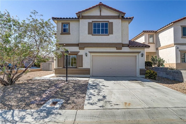 view of front facade featuring an attached garage, a tile roof, concrete driveway, and stucco siding