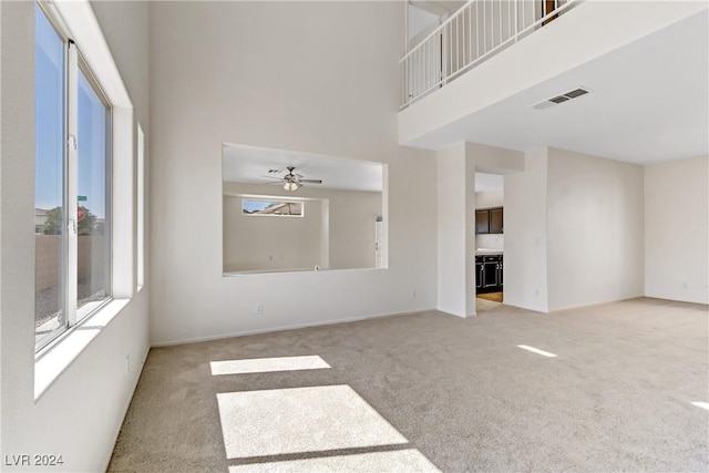 unfurnished living room with light carpet, visible vents, and a towering ceiling