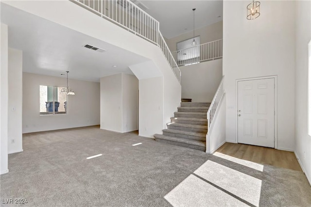 entrance foyer featuring visible vents, a notable chandelier, stairway, and a towering ceiling