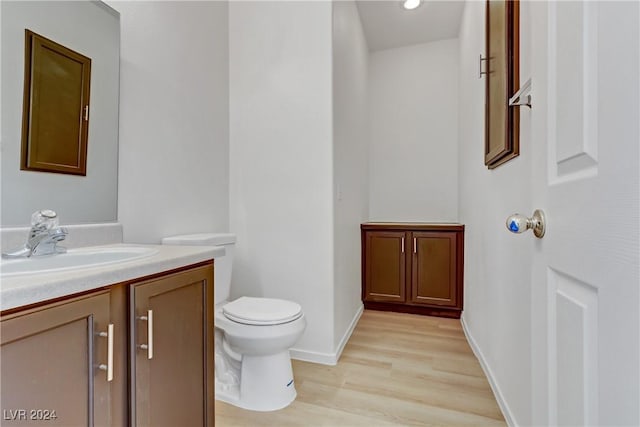 bathroom featuring baseboards, vanity, toilet, and wood finished floors