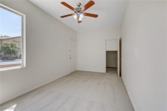 empty room with light colored carpet, ceiling fan, and baseboards