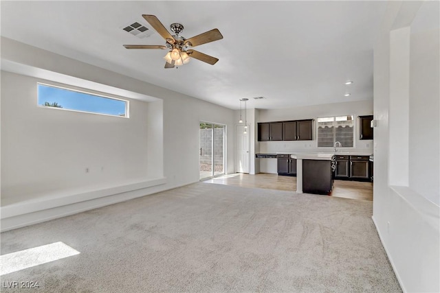 unfurnished living room with visible vents, a ceiling fan, and light colored carpet