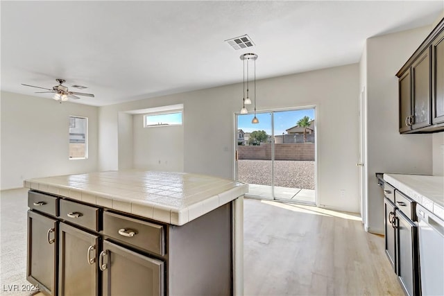 kitchen featuring visible vents, tile counters, dishwashing machine, decorative light fixtures, and dark brown cabinets