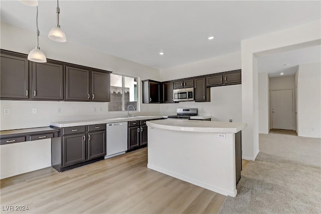 kitchen featuring stainless steel appliances, light countertops, a kitchen island, and decorative light fixtures