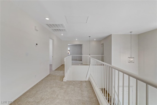 corridor featuring visible vents, an inviting chandelier, light carpet, an upstairs landing, and baseboards