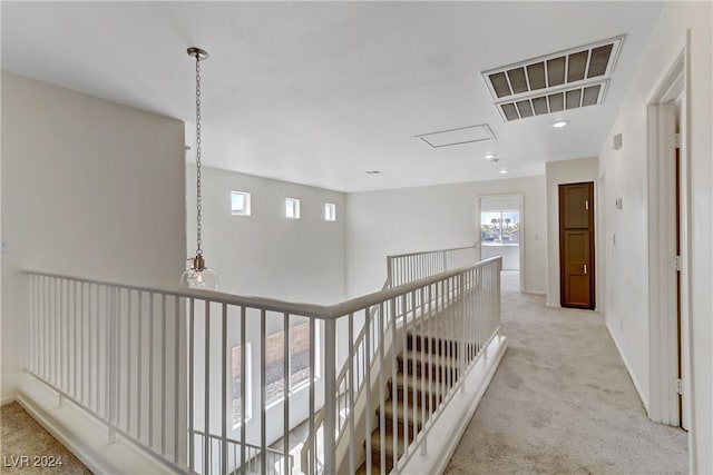 hall featuring an upstairs landing, visible vents, baseboards, and light colored carpet