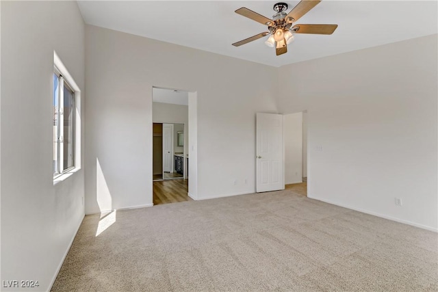 unfurnished bedroom featuring a ceiling fan, baseboards, light carpet, and a high ceiling