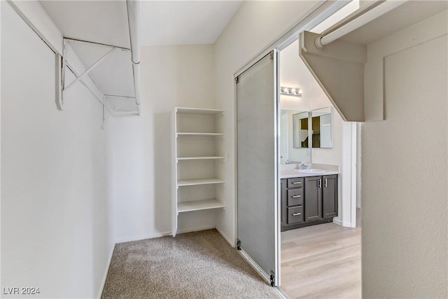 walk in closet with light carpet and a sink