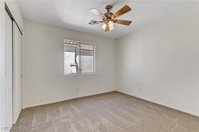 unfurnished bedroom with a ceiling fan, a closet, light carpet, and baseboards