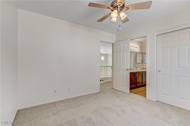 unfurnished bedroom with light carpet, ensuite bath, baseboards, and ceiling fan