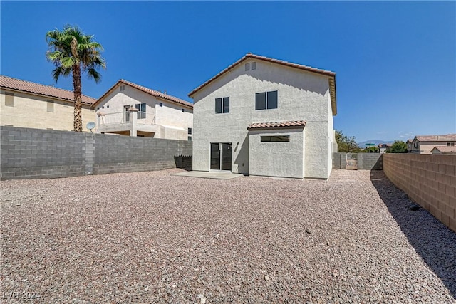 rear view of property with stucco siding, a fenced backyard, a tile roof, and a patio