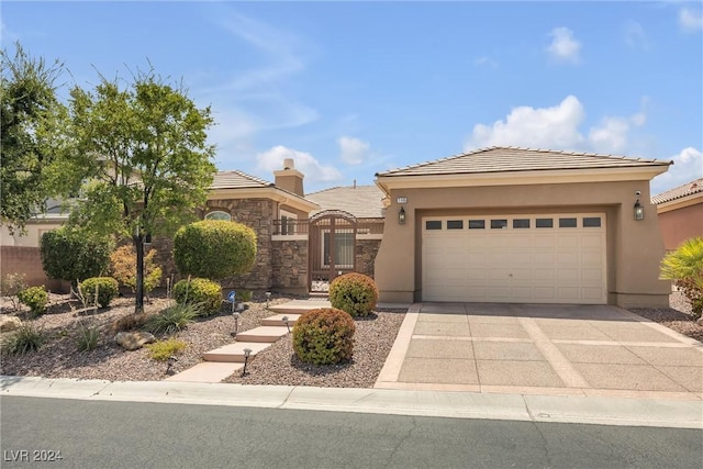 view of front of house featuring an attached garage, concrete driveway, a tiled roof, a gate, and stucco siding