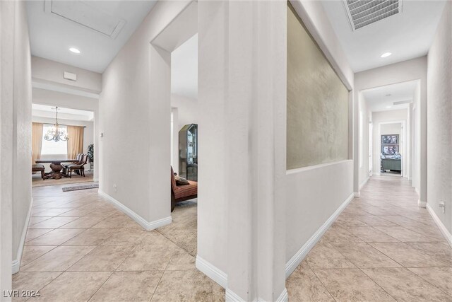 hall featuring light tile patterned flooring and a chandelier