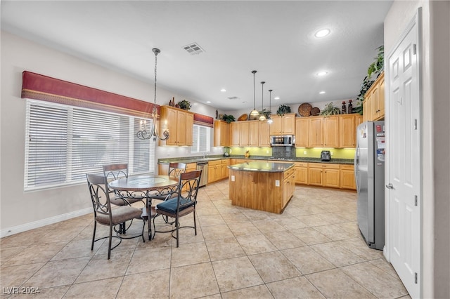 kitchen with light tile patterned flooring, a kitchen island, stainless steel appliances, and hanging light fixtures