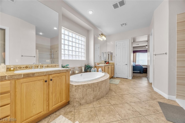 bathroom featuring tile patterned flooring, tiled tub, vanity, and a healthy amount of sunlight