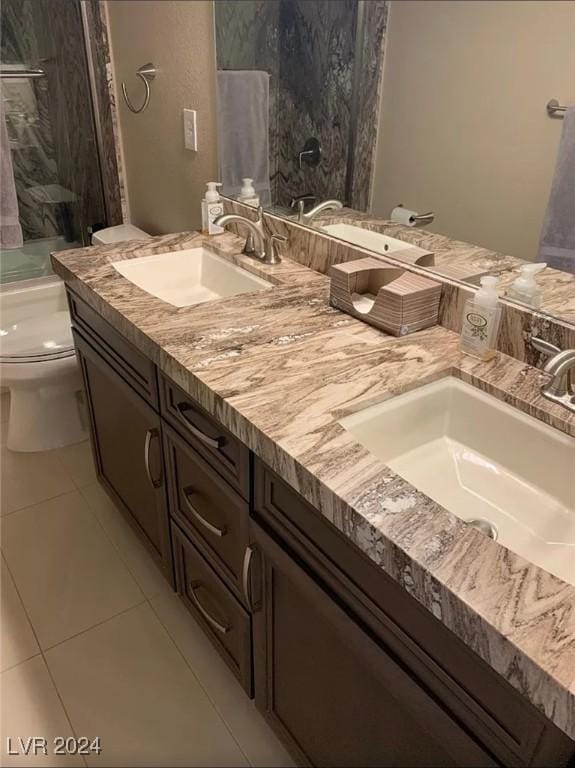 bathroom featuring tile patterned flooring, vanity, tiled shower, and toilet