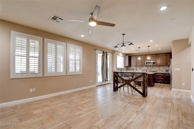 5301 Fairbranch Ln, Las Vegas, NV 89135 - kitchen featuring visible vents, decorative backsplash, a center island, a ceiling fan, and stainless steel appliances