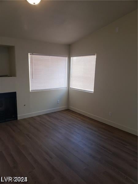 unfurnished living room with dark wood-style floors, a fireplace, and baseboards