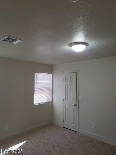 empty room featuring carpet and a textured ceiling