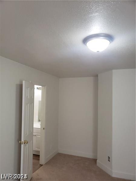 spare room featuring baseboards, light carpet, and a textured ceiling