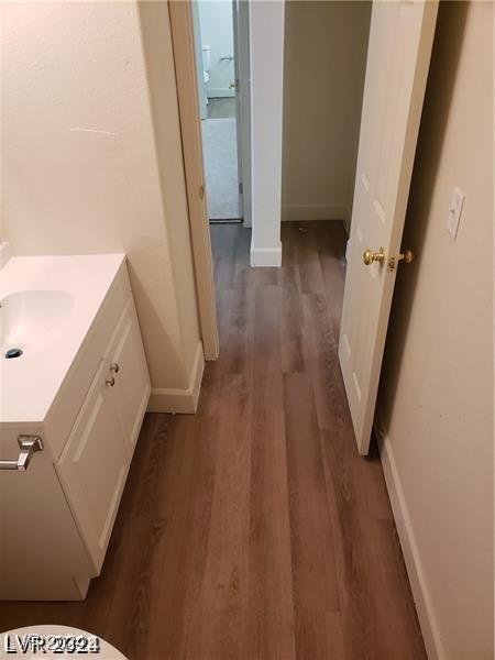 bathroom with baseboards, wood finished floors, and vanity