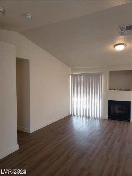 unfurnished living room with dark wood-type flooring and vaulted ceiling