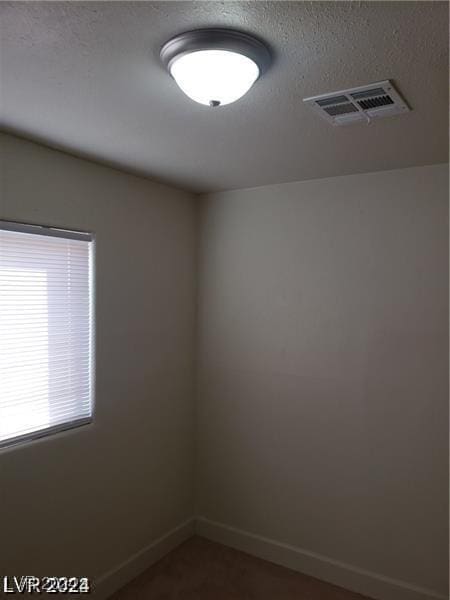 unfurnished room featuring visible vents, baseboards, and a textured ceiling