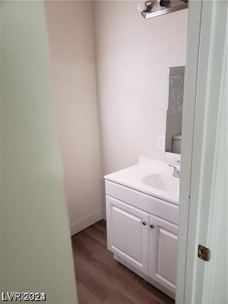 bathroom with hardwood / wood-style flooring, toilet, and vanity