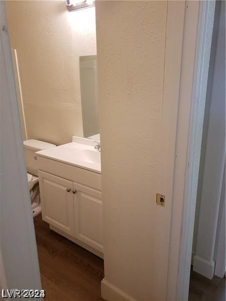 bathroom with vanity, toilet, and hardwood / wood-style floors