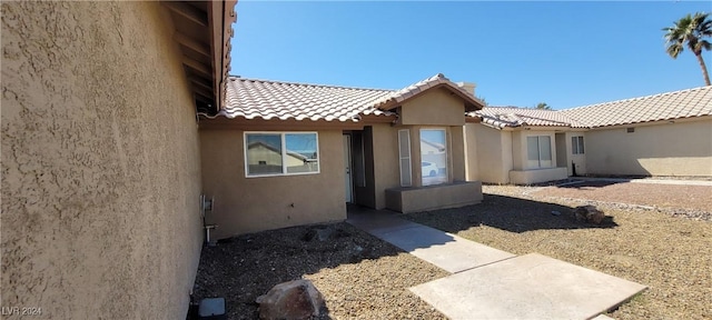 exterior space featuring stucco siding and a tiled roof