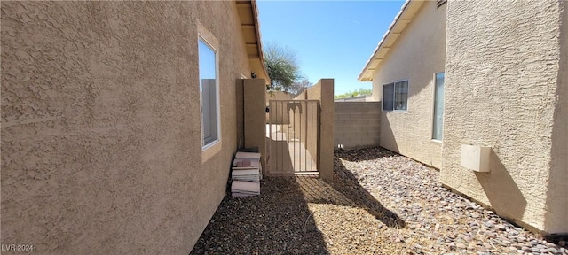 view of side of property with stucco siding and fence