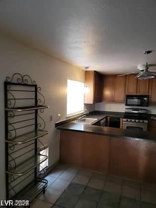 kitchen with stove, sink, and light tile patterned floors