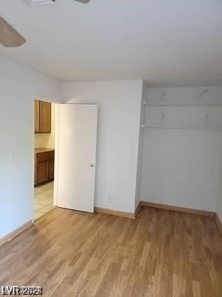 unfurnished bedroom featuring a closet, ensuite bath, and light wood-type flooring