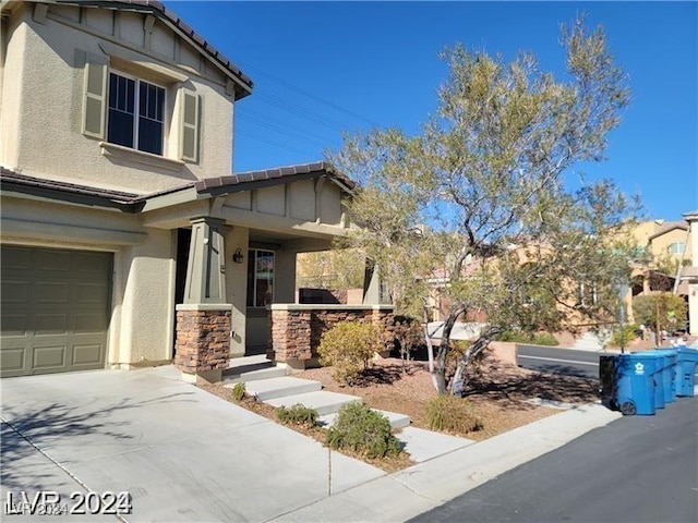 view of front of home featuring stucco siding, stone siding, driveway, and a tiled roof