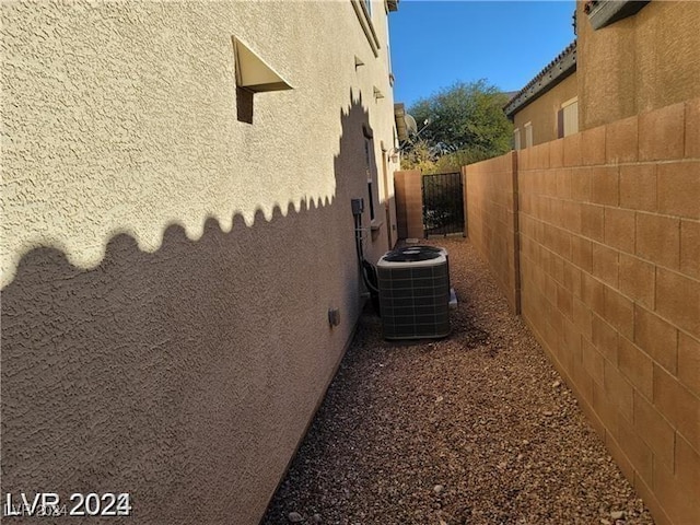 view of side of property with cooling unit, fence, and stucco siding