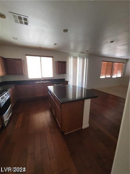 kitchen with dark countertops, visible vents, dark wood-style flooring, and stainless steel range with electric cooktop