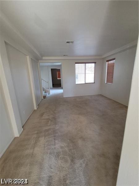 spare room featuring light carpet, visible vents, and stairs