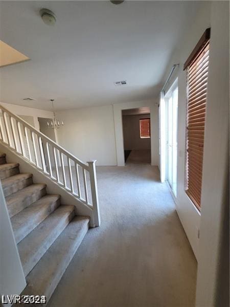 hall featuring light carpet, stairway, and visible vents