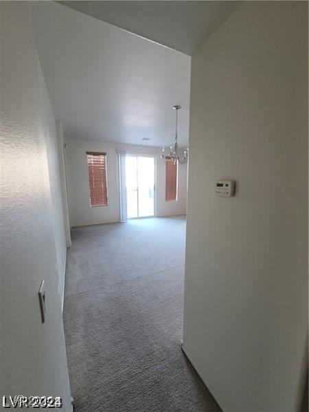 empty room featuring carpet and a chandelier