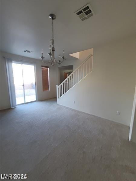 unfurnished living room with visible vents, an inviting chandelier, and stairway