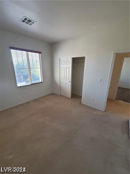 unfurnished bedroom with visible vents, light carpet, and a closet