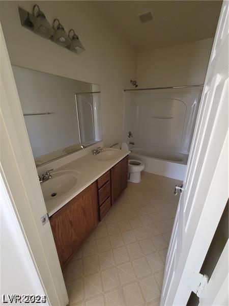 bathroom featuring double vanity, toilet, shower / tub combination, and a sink